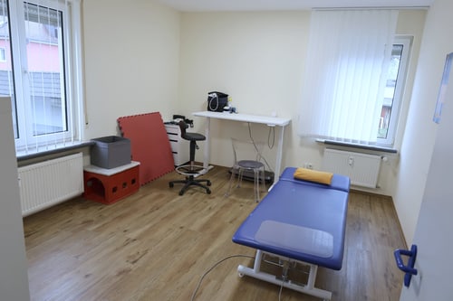 Behandlungsraum mit elektrischer Therapieliege und höhenverstellbarem Tisch