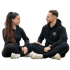 Mann und Frau sitzen auf dem Boden, tragen schwarze Sportkleidung und schauen sich an.