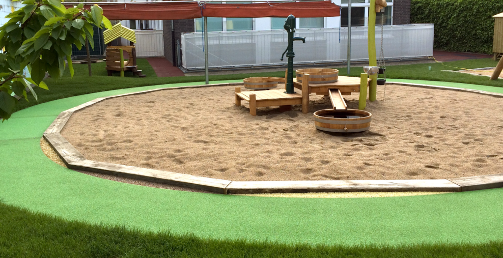 Spielplatz mit Sandkasten und Wasserpumpe der Kita Grethenwichtel