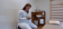 Physiotherapeutin schreibt in Praxisraum mit Tablet und Eingabestift neben einer Therapieliege und Sprossenwand.