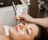Nahaufnahme einer Frau auf einer Liege, während eine Hand ein Microneedling-Gerät hält.
