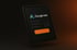 Dunkles Tablet mit dem Google Ads-Logo, einem Diagramm und einem orangefarbenen Schaltflächenelement auf dem Bildschirm.