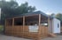 Ein modernes Mobilheim mit Holzbalkon, der Aufschrift "3V HOLIDAY RESORT Villa Limoncello" und einer weißen Seitenwand.