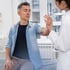Patient sits on an exam table as a female doctor checks his arm.
