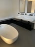 Modernes Badezimmer mit einem fugenlosem grauen Boden und weißen Wänden