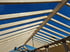 Dachstuhl aus Holzlatten vor blauem Himmel.