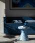 Blauer Terrazzo-Beistelltisch mit Büchern und Kerze neben einem dunkelblauen Sofa mit Kissen und Schatten.