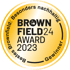 Goldener Brownfield24 Award 2023 mit Text "Bestes Brownfield: Besonders nachhaltig – Gewinner" und Fabriklogo.