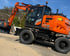 Oranger Hitachi Mobilbagger ZX175W mit Greifer auf Schotterweg.