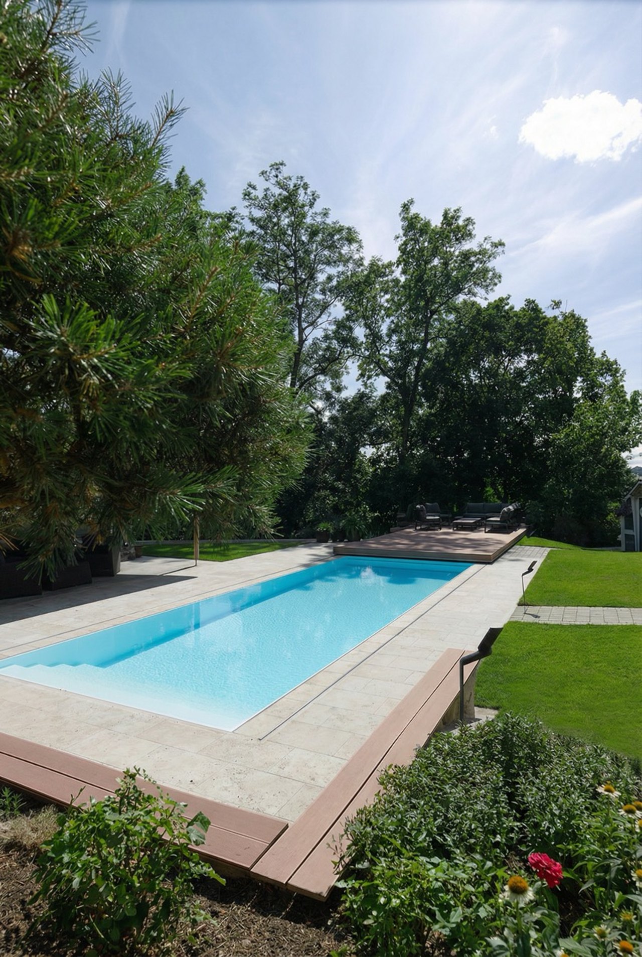 Rechteckiger Pool mit blauem Wasser und Steinterrasse