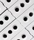 Close-up of gray perforated bricks stacked diagonally with circular holes.