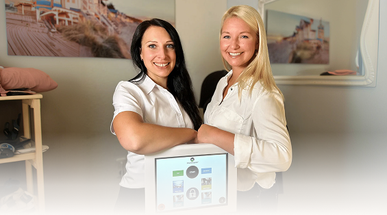 Zwei Mitarbeiterinnen von BodyHub neben dem Bedienterminal des Pelvipower-Stuhls