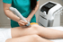 A physical therapist uses a shockwave therapy device on a patient's knee.