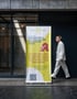 Roll-up-Banner der Sonnen-Apotheke mit QR-Code vor einem Gebäude, an dem ein Mann im hellen Anzug vorbeiläuft.