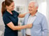 Pflegekraft hilft einem älteren Patienten beim Ankleiden und unterstützt ihn sicher im Alltag zu Hause.