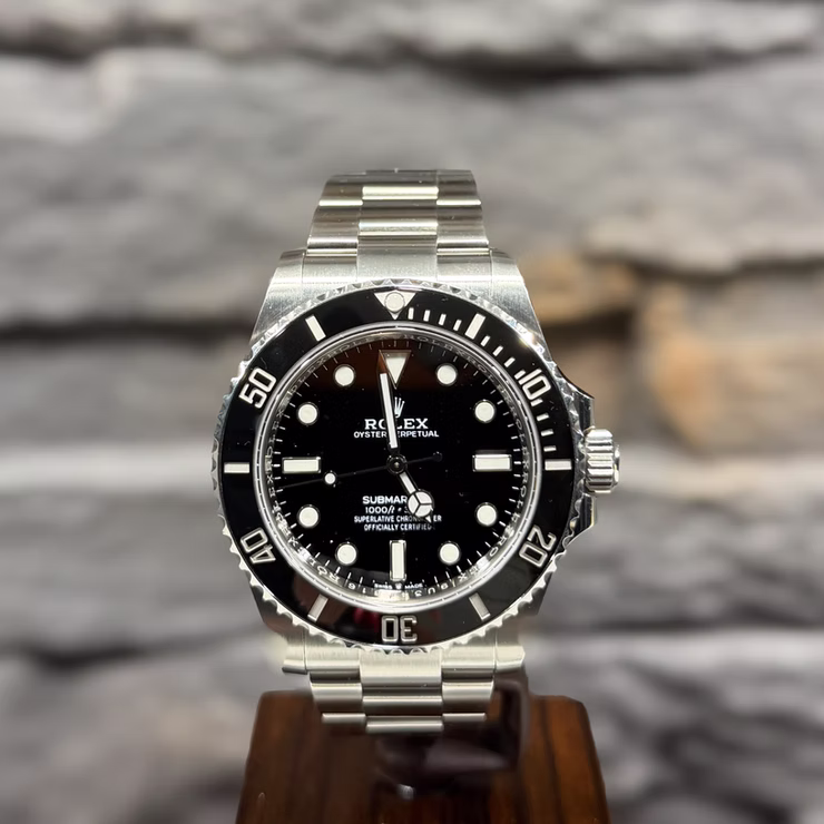 Silberne Rolex Submariner Uhr mit schwarzem Zifferblatt und Lünette, "ROLEX OYSTER PERPETUAL SUBMARINER 1000ft" Text.