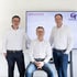 Drei Männer in weißen Hemden vor einem Bildschirm mit dem Text Technik für Menschen, Menschen für Technik und GfS Logo.