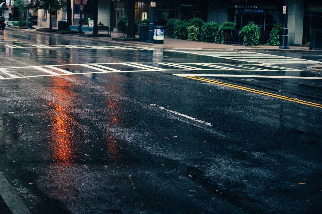Wet asphalt road reflecting grey daylight, the slick surface the first rain of the season leaves on roads around Hanford, California