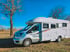 Silbernes Wohnmobil Zefiro 288 TL auf einem Feldweg unter blauem Himmel.