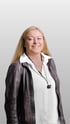 Andrea Kreinhöffner, freundliches Business-Porträt einer Frau mit langen blonden Haaren, Lederjacke und weißer Bluse vor grauem Hintergrund.
