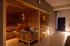 Moderne Sauna mit Glasfront, Holzbänken und indirekter Beleuchtung in einem Wellnessbereich.