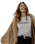 Lachende Frau mit langem braunem Haar, die ein graues T-Shirt mit der Aufschrift "OCEVOO" und einen braunen Strickcardigan trägt.