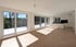 Heller, offener Wohnraum mit Holzboden, großen Fenstern, Balkon und integrierter Küche mit Kochinsel.