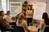 Eine Frau leitet eine Weiterbildung für Pflegefamilien vor einem Flipchart und einem Roll-up Banner der Karawane.