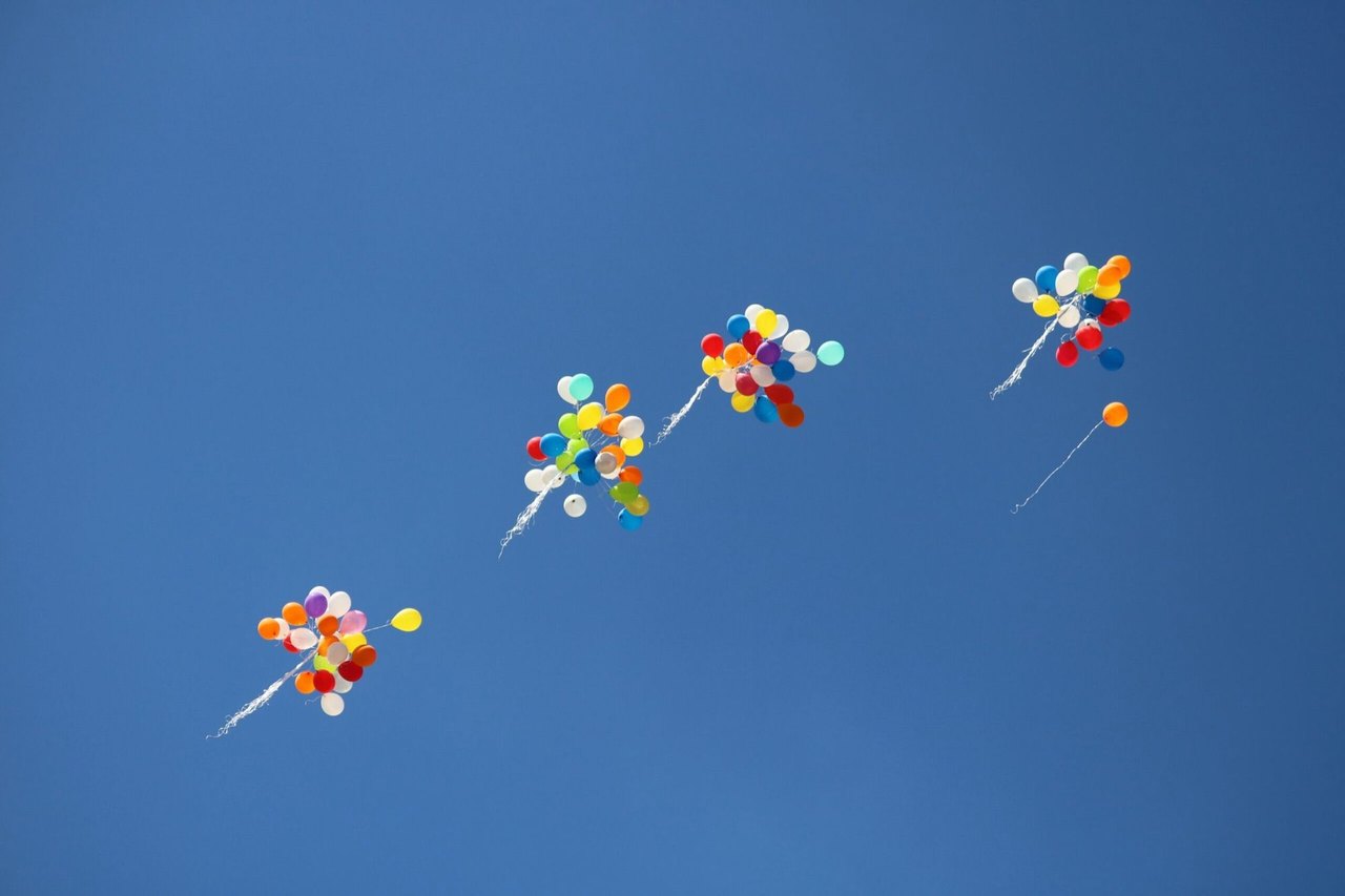 Bunte Luftballons steigen in den blauen Himmel