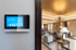 Smart-Home-Bedienfeld an einer Wand mit Blick auf ein Wohnzimmer.