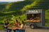 Drei Personen essen Pinsa an einem Tisch vor einem Food-Truck mit „PINSA“-Schild. Im Hintergrund grüne Weinberge.