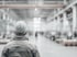 Rückenansicht eines Arbeiters mit Schutzhelm in einer großen Fabrikhalle.