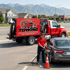 Towing Sandy fuel delivery service refueling a stranded sedan on the roadside with a mobile fuel truck and safety cones in place.