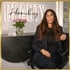 Frau mit Brille und langen braunen Haaren sitzt vor einer Rezeption mit der Leuchtschrift "BEAUTY Hamburg".
