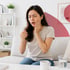 Woman sitting on a sofa, grimacing in pain and holding her jaw.