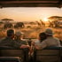 Familie im Safari-Jeep bei Sonnenuntergang, Junge beobachtet Giraffe mit Fernglas