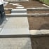 Gartenanlage mit Granitstufen, Pflastersteinen und Natursteinmauern auf vorbereitetem Erdboden.