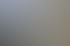 Ein Mann montiert mit einem Akkuschrauber eine weiße Terrassenüberdachung aus Metall unter blauem Himmel.