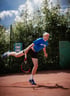 Tennismatch auf einem roten Sandplatz mit einem markanten, historischen Wasserturm im Hintergrund, umgeben von Bäumen und blühenden Pflanzen.