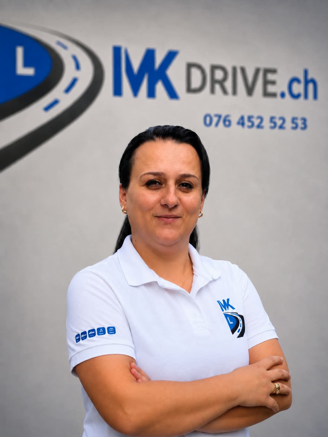 Gili, Instruktorin für den Nothelferkurs bei MK Drive, vor der Wand mit dem MK-Drive-Logo