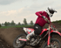 Motocross-Fahrer in rotem Trikot und weißem Helm fährt mit einer roten Honda-Maschine durch eine erdige Kurve.