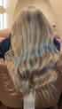 Rückansicht von langem, gewelltem Haar mit blonden Balayage-Highlights und dunklerem Ansatz.
