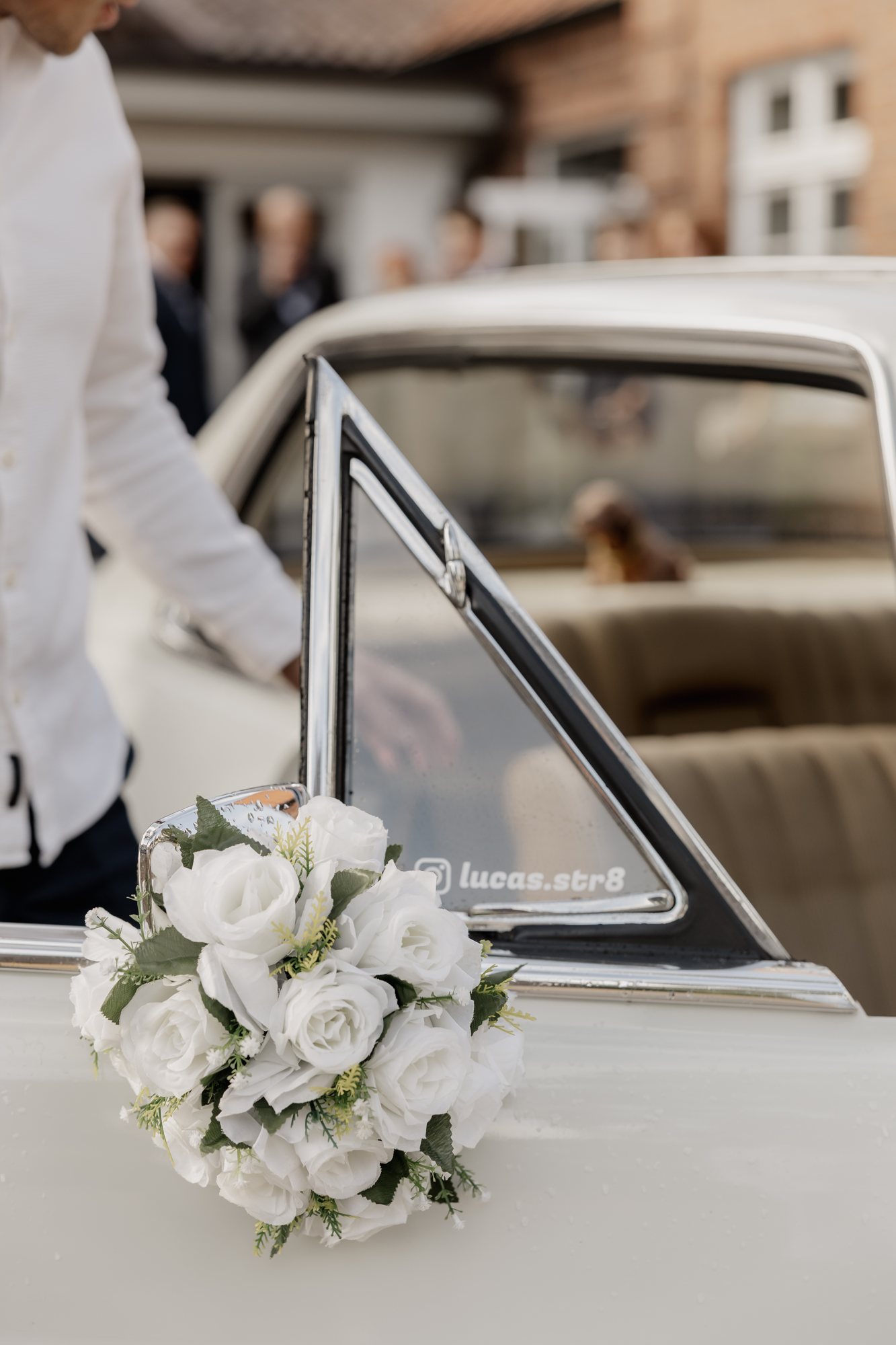 Brautstrauß aus weißen Rosen an der offenen Tür des Hochzeitsautos