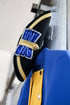 Ein schwarzer Zweispitz mit goldener Borte und blauer Kokarde hängt über einer blau-gelben Uniformjacke.