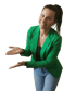 Lächelnde Frau in grünem Blazer und Jeans, die mit beiden Händen auf etwas zeigt.