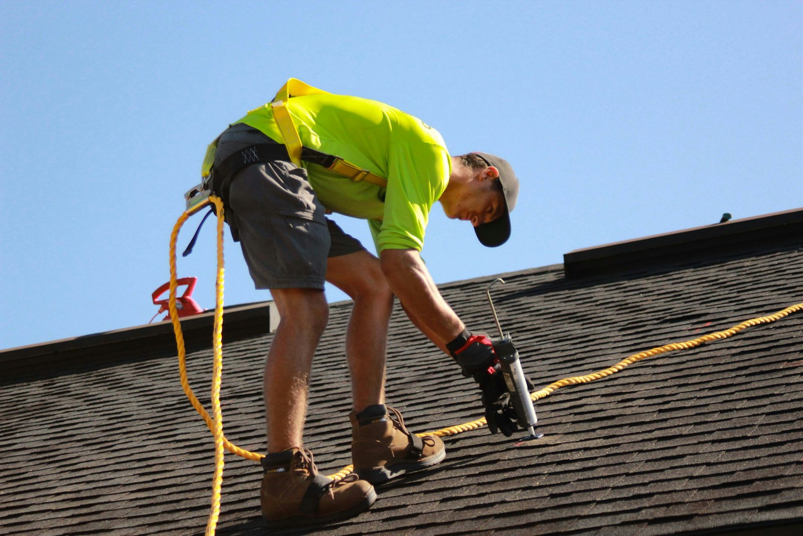 Roofer kneeling on a shingle roof working on a localised repair