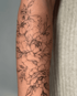 Ein filigranes Fineline-Tattoo mit Pfingstrosen und Blättern in schwarzer Tinte auf einem Unterarm.