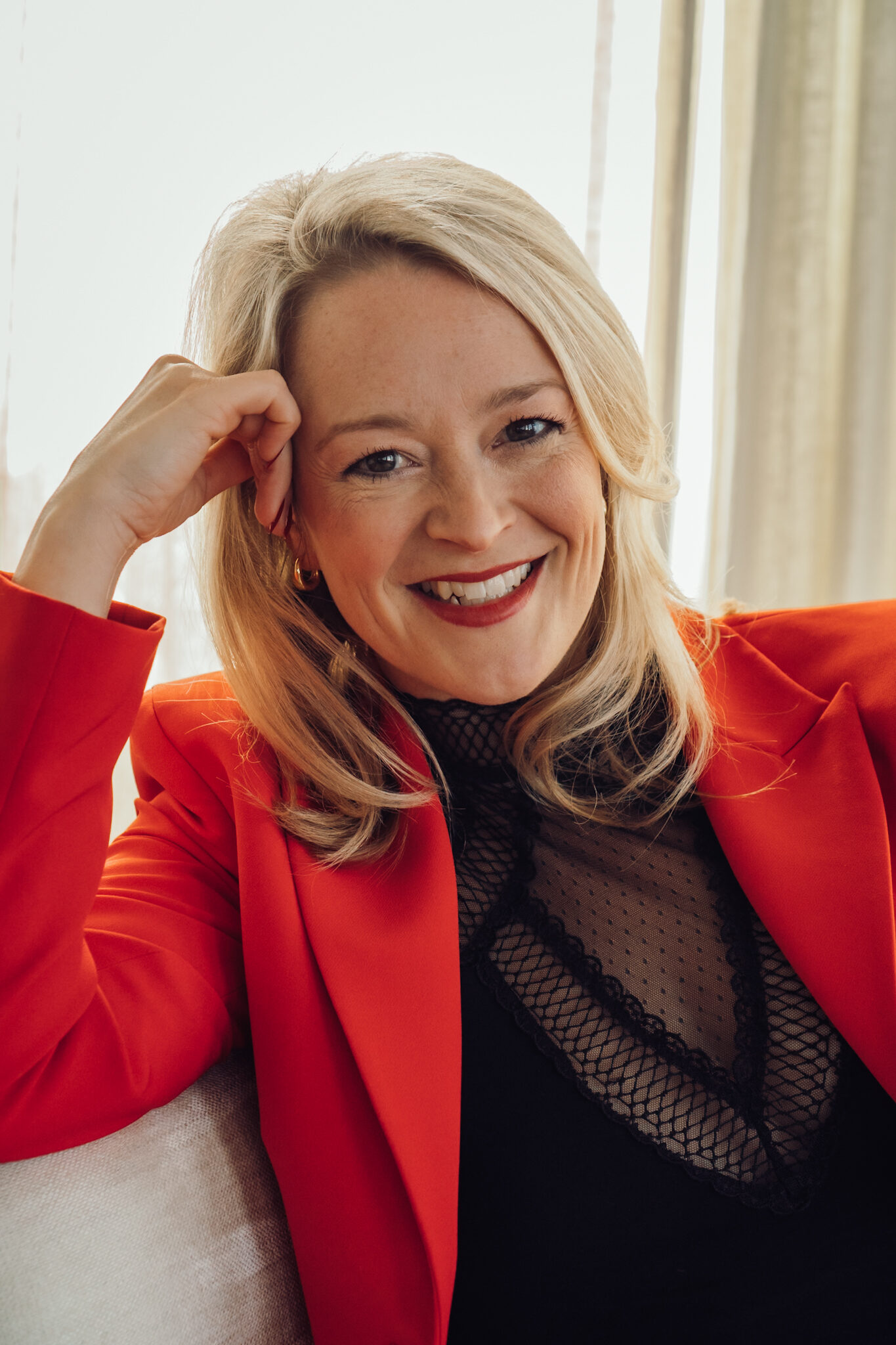 Mandy-Marie Mahrenholz im roten Blazer, lachend, die Hand am Kopf