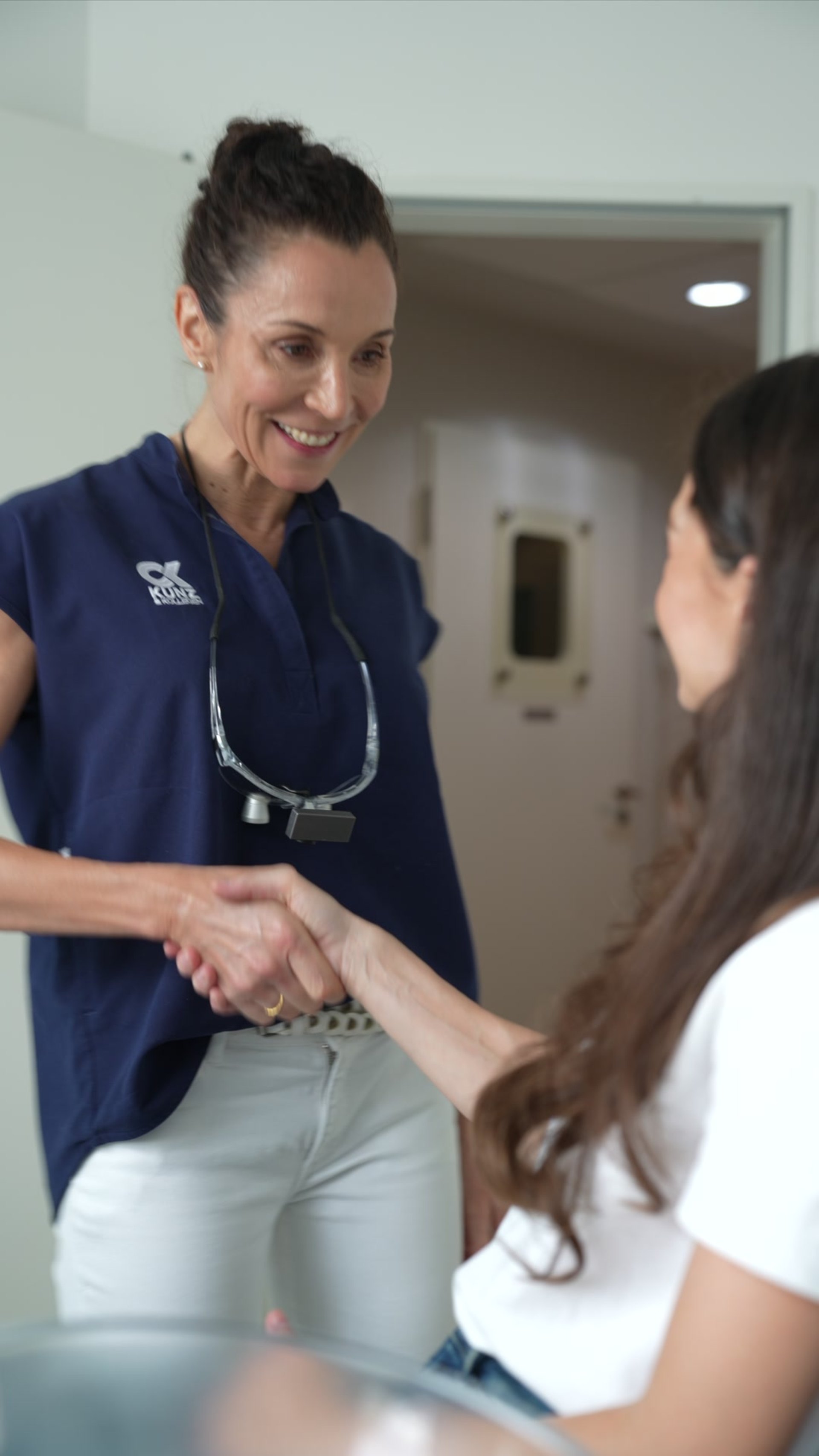Zahnärztin begrüßt eine Patientin im Behandlungszimmer