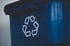 Nahaufnahme einer blauen Mülltonne aus Kunststoff mit einem weißen Recycling-Symbol aus Pfeilen auf der Vorderseite.